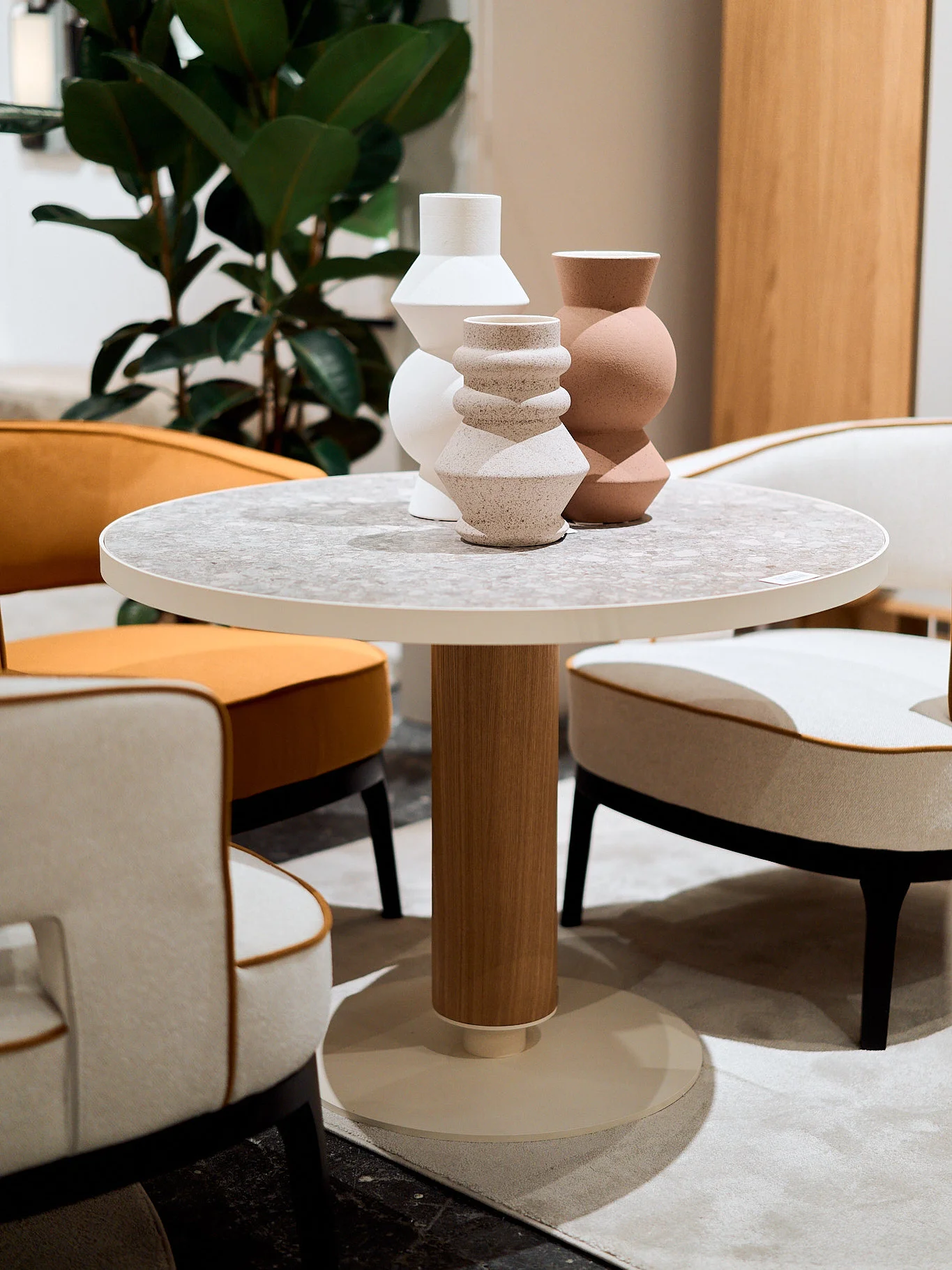 Colección de jarrones de cerámica mate con volúmenes orgánicos y geométricos sobre mesa redonda de exposición.